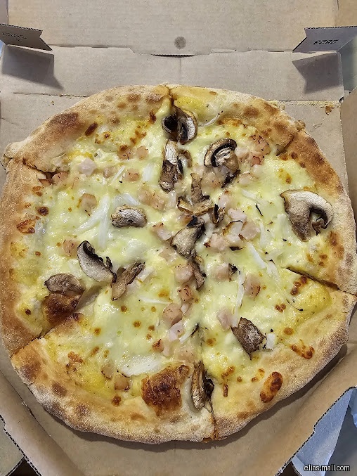 A Domino's pizza with mushrooms and white sauce is in a cardboard box.