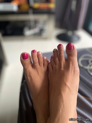 A pair of feet with painted toenails in pink and gold.
